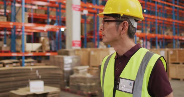 Asian male worker wearing safety suit and walking in warehouse