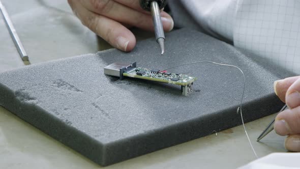 Manual soldering of electronic components on a PCB board, close up