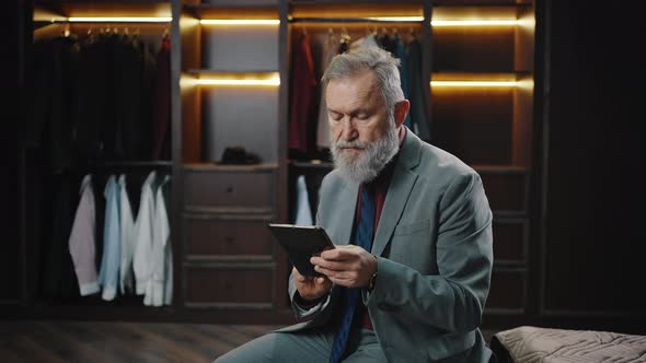 Successful Mature Businessman Checking His Business Plan on Digital Tablet Sitting at Luxury