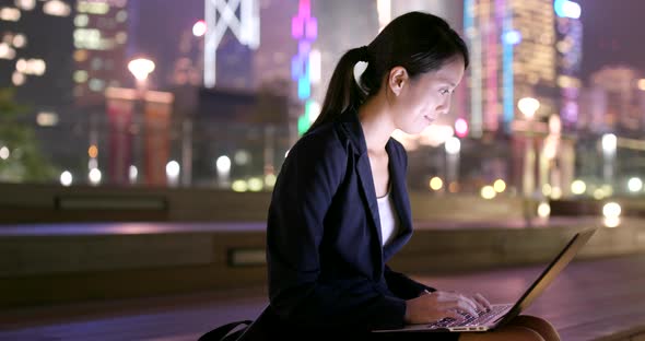 Businesswoman working on notebook in city at night