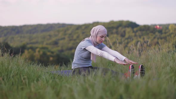 Woman in Hijab Stretching Body at Summer Park