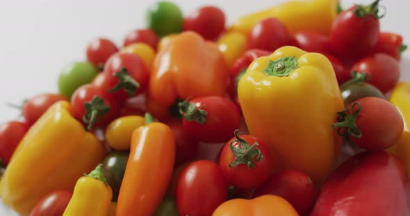 Video of fresh peppers and tomatoes spinning on white background