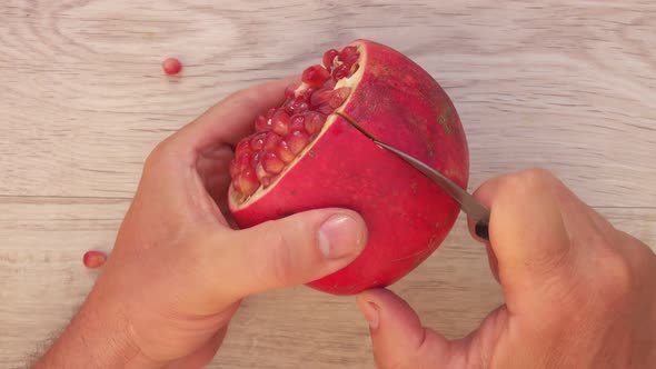 Top View of the Hands Cutting a Juicy Red Ripe Pomegranate Into the Six Pieces