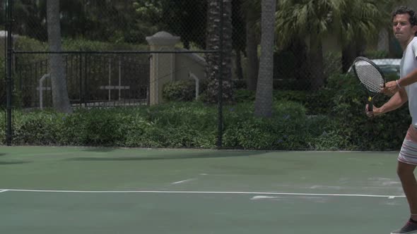 A young man playing tennis with his girlfriend.