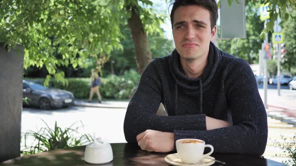 Portrait of Crying Sad Young Man Sitting in Cafe Terrace