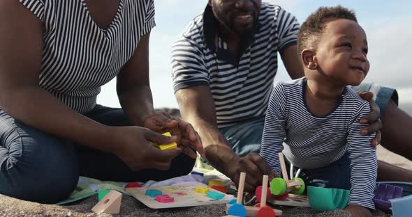 Happy african parents having fun on the beach with their son - Love concept