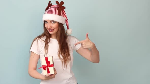 Woman White Tshirt with a Red Santa Claus Hat on a Pastel Blue Background