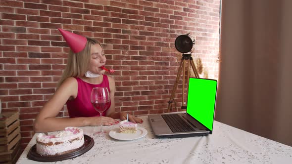 A happy woman is celebrating her birthday with a festive hat and a Piper looking at a modern laptop