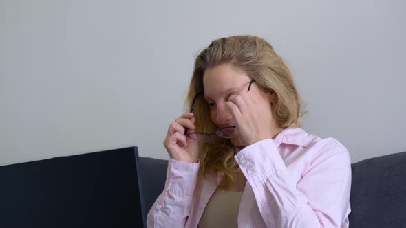 A Beautiful Young Female Student Puts on Glasses to Work on a Laptop Keyboard