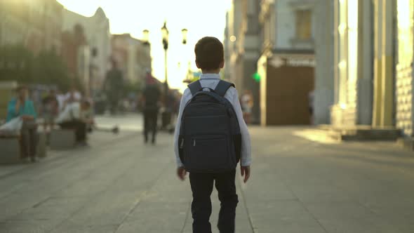 Rear View of a Schoolboy Rushing Home After School Walking Down the Street During Rush Hour