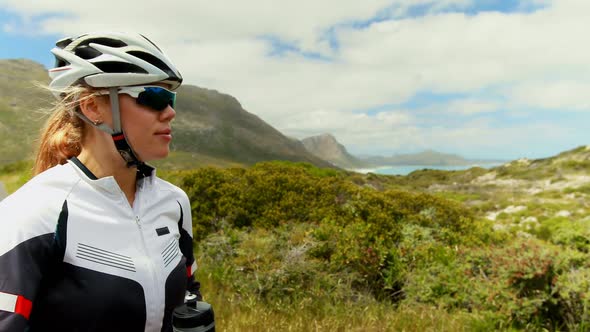 Female cyclist drinking water at countryside road 4k