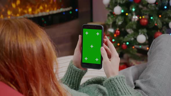 Woman holding mobile phone with a green screen
