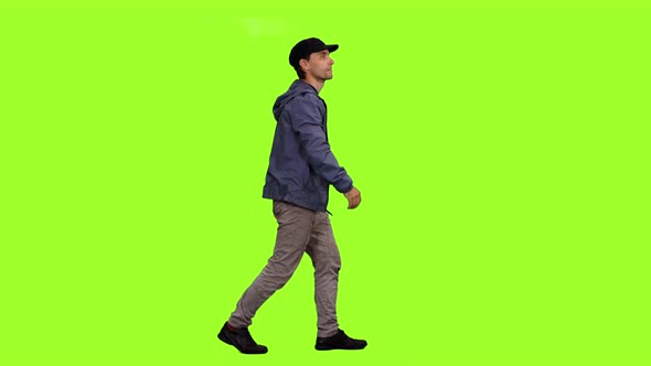 A Man in Casual Wear Walks on Green Background