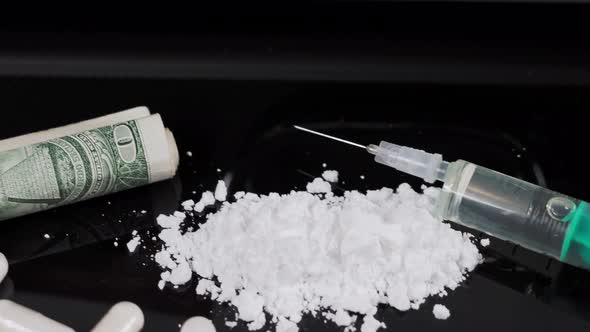 Money and drugs on a black glass table. Money, syringe and drugs.