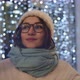 A beautiful smiling brunette in glasses in a winter hat in the night city in the background - VideoHive Item for Sale