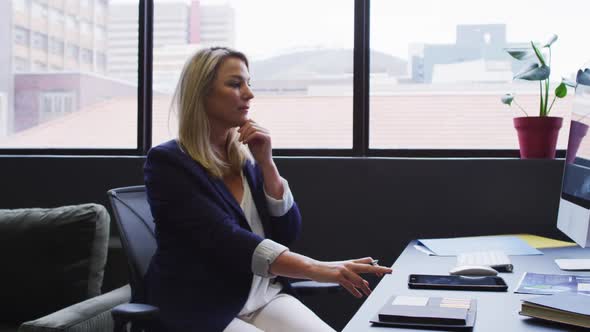 Caucasian businesswoman sitting at desk using a computer in modern office