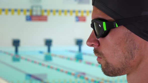 A Professional Swimmer Looks Ahead and Takes Deep Breaths at an Indoor Pool - Face Closeup