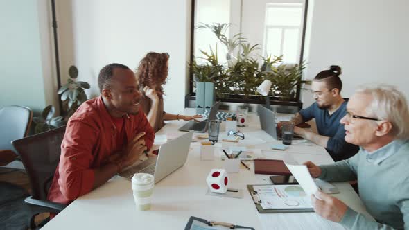 Diverse Mixed-Aged Business Team Working at Table in Open Space Office