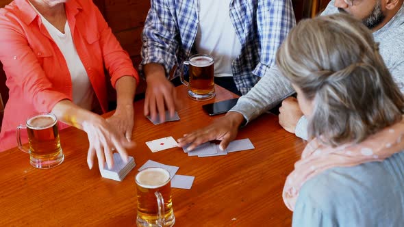 Happy friends playing cards while having glass of beer 4k