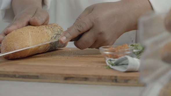Man Cutting a Piece of Bread with a Knife in the Kitchen on a Sunny Day Shot on Red Camera.