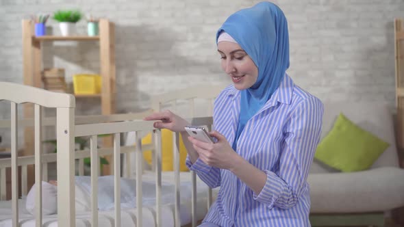 Muslim Young Woman Is a Mother By the Bed in the Nursery