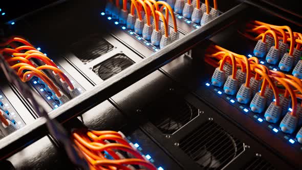 Countless orange cables in a  server cabinet lit by a single spotlight. 4KHD