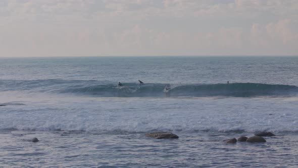 A Surfer manages to catch a wave while another two wait for theirs in malibu california