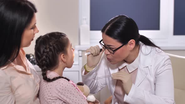 Pediatrician Examining Child Patient's Throat