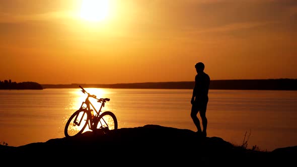 Sports bike and bicyclist at sunset near the river.