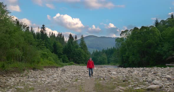 A Tourist with a Backpack Walks Through a Mountain Valley