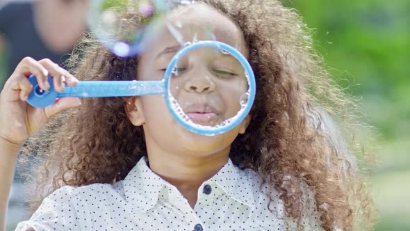 Little African Girl Blowing Soap Bubbles at Camera alt