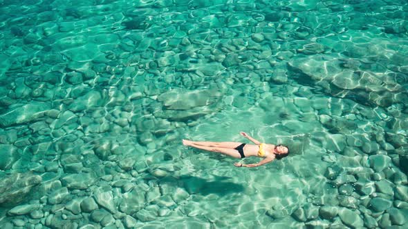 A Woman Swims in Blue Sea Water in the Bay. Nature and Relaxation, Top View