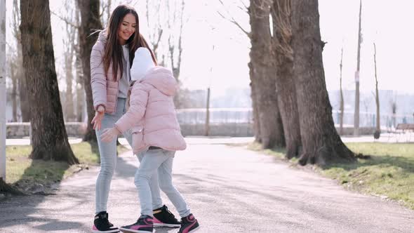 Beautiful Mother Is Walking with a Cute Daughter in a Park