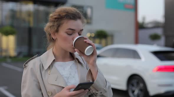Woman Drinking Coffee in City Using Smartphone