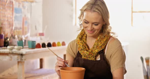 Beautiful female potter painting on pot