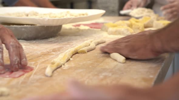 human hands, modelling  and making a typical type of italian pasta on a wood table with flour water