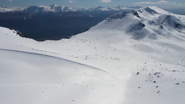 Dolly in lowering over snow covered Piltriquitron Hill, mountains in background, El Bolsón, Patagoni