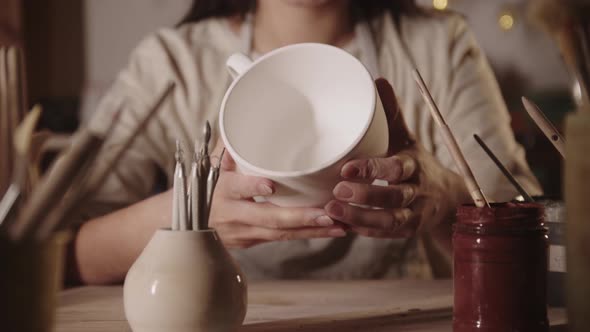 Young Woman Potter Holding Big White Tea Cup Made Out of Clay