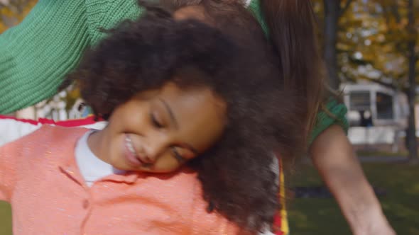 Cheerful Caucasian Mom Laughing and Playing with Little Afro Girls in Park