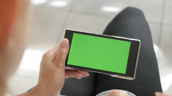 Display of mobile phone with green screen  in blond female hands 4K 2160p 30fps UltraHD footage - Bl