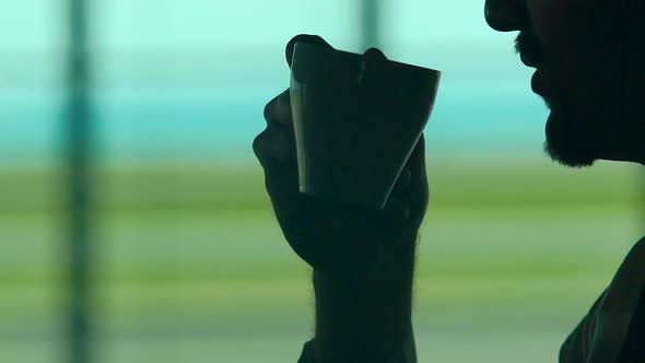 Male Silhouette Drinking Coffee in Cafe Against Big Window, Suburban Sport Club