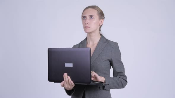 Happy Young Blonde Businesswoman Thinking While Using Laptop