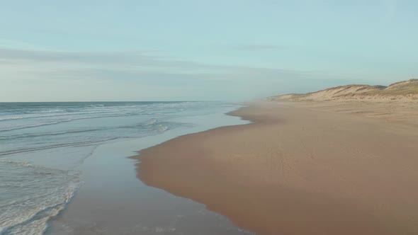 Empty Endless Beach with Dunes and Blue Ocean, Aerial High Angle Forward Into the Distance in