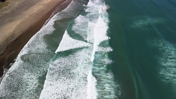 Vertical pan from drone over Piha black sand beach in NZ