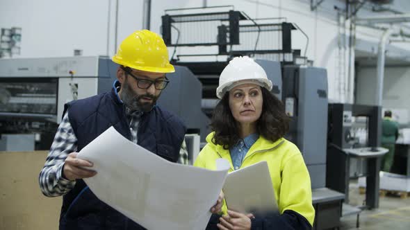 Front View of Printing Employees Inspecting Plan of Building