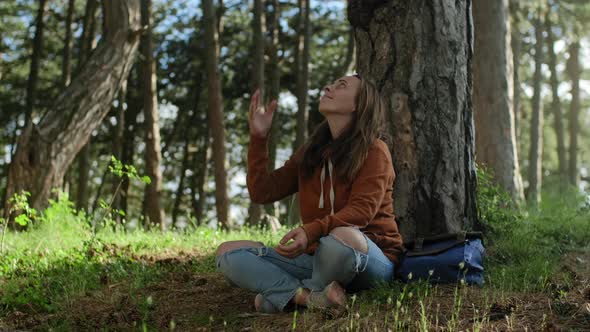 Peaceful woman sitting in pine forest and meditation, relaxation and healthy lifestyle