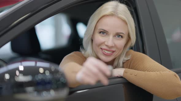 Closeup of Charming Blond Woman with Grey Eyes Looking at Camera Smiling and Opening Car Key