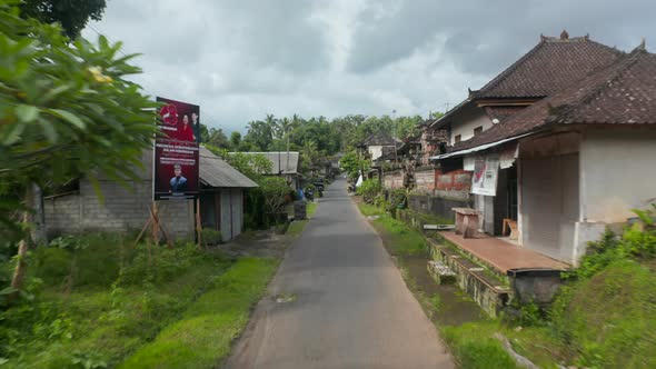 Low Flying Aerial Pov Shot Down the Traditional Street in the Residential Community in Bali