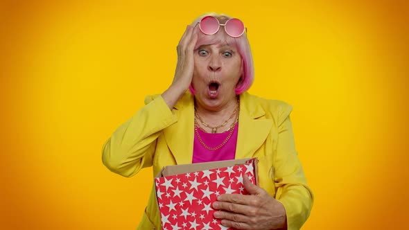 Amazed Senior Grandmother Woman Opening Gift Box and Smiling Joyfully Satisfied with Nice Present