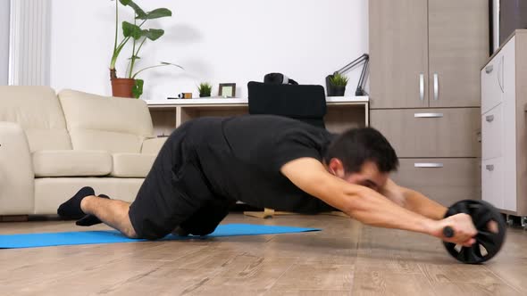 Athletic Man Doing Abs Exercises with an Ab Wheel